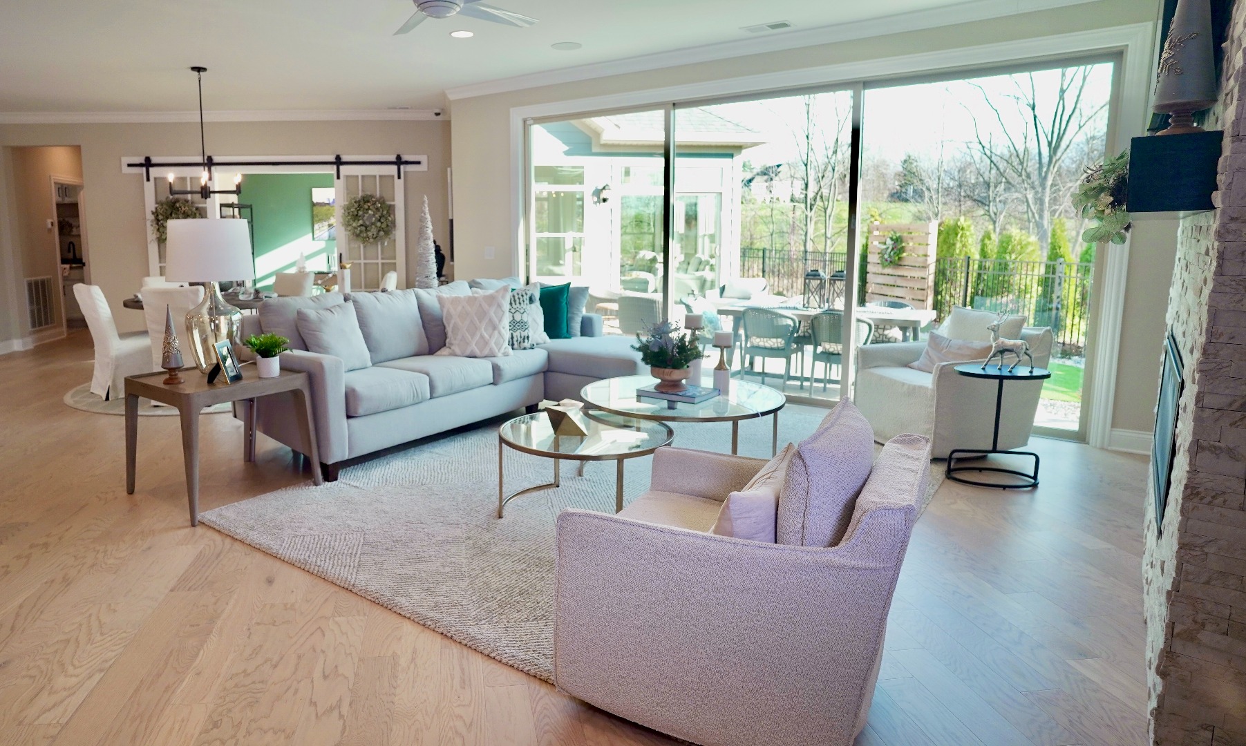 An open living room space featuring a huge wall-length window into the courtyard. A study/den is visible in the background,