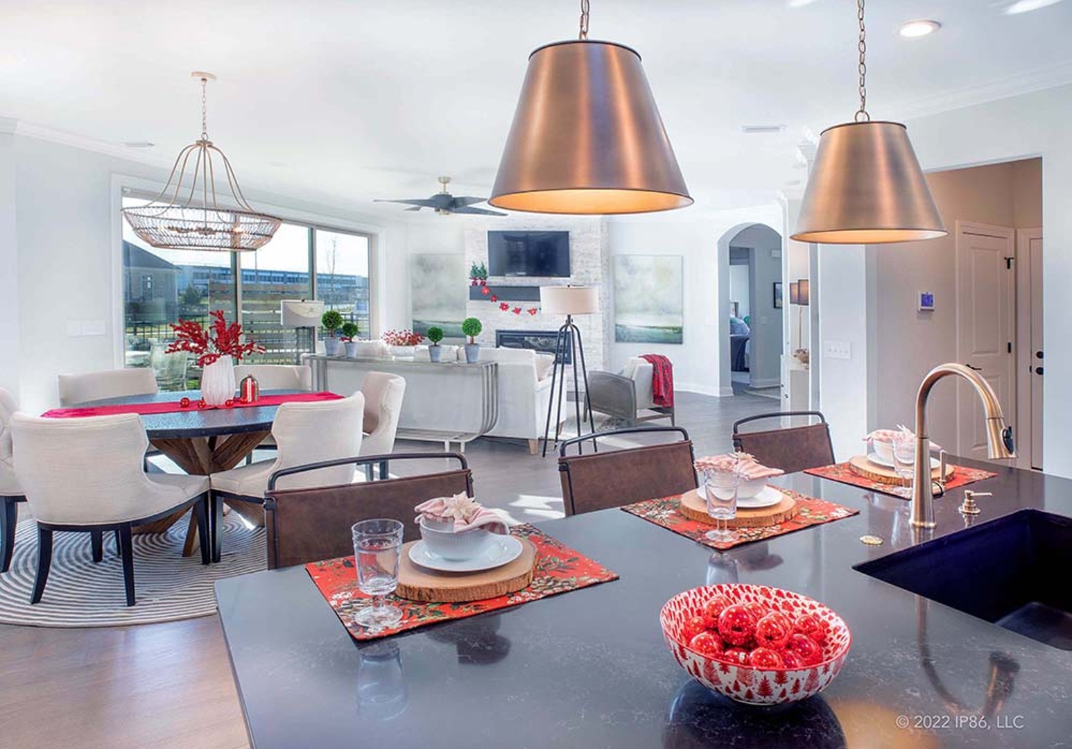 A festive dining and living space is visible over the kitchen counter. Bright red holiday decor is set off by gold fixtures.